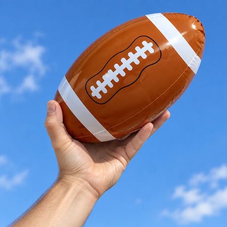 22 cm inflatable American football held in one hand ready to throw against a blue sky, in square format