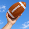 22 cm inflatable American football held in one hand ready to throw against a blue sky, in square format