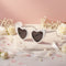 Heart-shaped sunglasses with pearl details on a decorative surface with flowers and ribbons.