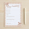 Baby predictions sheet with checkered border and pen on wooden surface