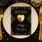 A black and gold New Year's Eve place card featuring a gold heart and personalized text, styled on a white plate with gold cutlery and a black tablecloth.