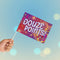 Hand holding a colorful sign with 'DOUZE POINTS!' text against a blurred background