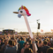 Adult Holding Inflatable Unicorn Hobby Horse High in Festival Crowd
