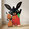 Bing and Flop cardboard cutout on a wooden floor against a neutral wall with soft light and shade, in square format