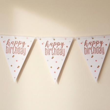Birthday bunting with translucent white bias binding against a softly lit cream wall