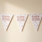 Birthday bunting with translucent white bias binding against a softly lit cream wall