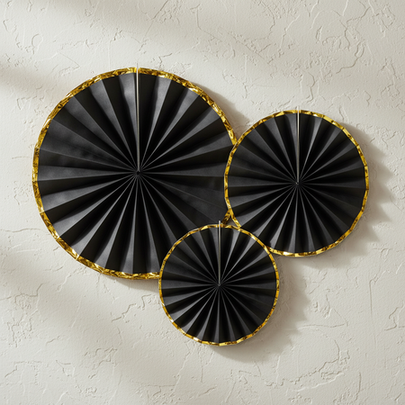 Black and Gold Paper Fan Decorations on Textured Wall
