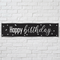 Black and silver Happy Birthday banner on a white brick wall with soft light and shade, in square format