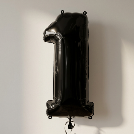 Black number 1 balloon against a neutral background with soft light and shade, in square format