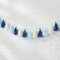 Blue and white tassel garland on a white brick wall