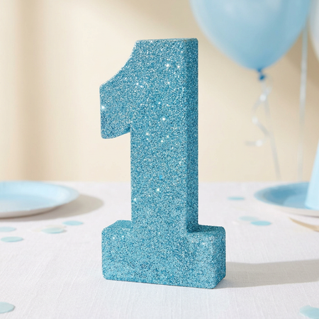 Blue glitter number 1 decoration on a white tablecloth with soft pale blue first-birthday styling
