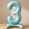 Blue number 3 balloon on a wooden table with a neutral background and soft light and shade, square format
