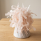 Blush-pink balloon weight close up on a wooden table with a neutral background, in square format