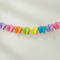 A pastel rainbow butterfly garland with colorful paper-cut butterflies strung across a plain light background.