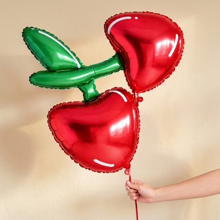 Cherry balloon against a cream wall with soft natural light and shade