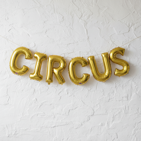 CIRCUS Gold Foil Balloons as Bunting on White Textured Wall