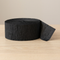 Close-up black streamer roll on a wooden table with a neutral background, in square format