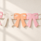 Close-up of peach, pink and ivory paper bow bunting against an off-white wall