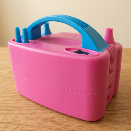 Close-up of the pink and blue balloon inflator on a wooden table with a neutral background, in square format
