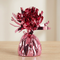 Close-up of the pink foil balloon weight on a matching wooden table with a neutral background, in square format