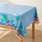 Close-up of the tablecloth draped over a wooden table corner, with a wood floor and neutral background in square format