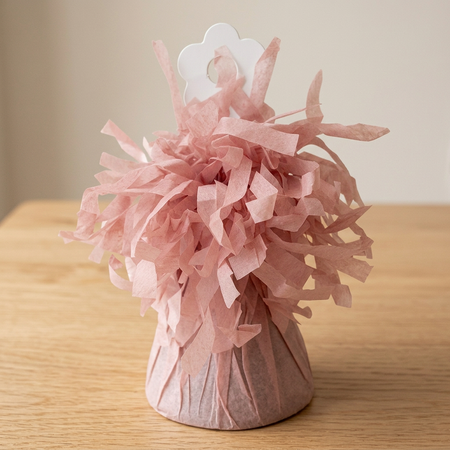 Dusky-pink balloon weight close up on a wooden table with a neutral background, in square format
