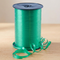Emerald green curling ribbon reel on the matching wooden tabletop with a neutral background and soft lighting, in square format