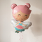 Fairy balloon floating with pink curling ribbon against a neutral wall with soft light and shade, close up in square format