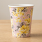Floral paper cup on a wooden table with a neutral background, in square format