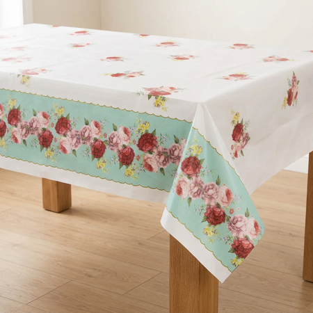 Floral tablecover with wooden table legs, a wood floor and neutral room background, in square format
