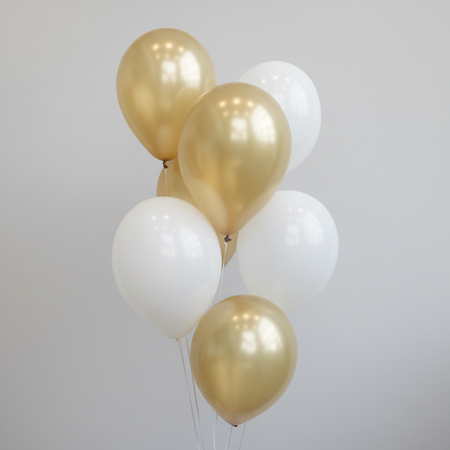 Gold and white balloon bunch on a neutral background