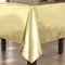 Gold foil table cover on a table with dark legs and a floor background, square format