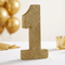 Gold glitter number 1 decoration on a white tablecloth with soft gold celebration styling