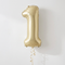 Gold number one balloon floating with gold curling ribbon against a softly lit white wall, in square format