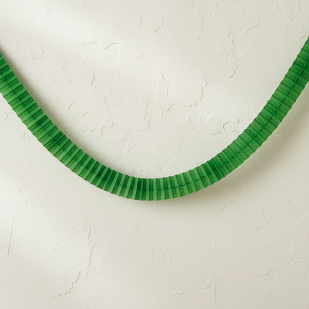 Green Tissue Paper Garland Draped on Cream Textured Wall