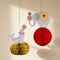 Hanging circus decorations against a cream wall with soft light and shade, in square format
