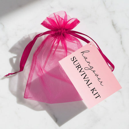 Pink organza bag with a pink tag labeled 'Hangover Survival Kit' on a white background