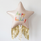 Happy Birthday star balloon with gold fringe and gold curling ribbon floating against a white wall with soft light and shade