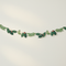 Holly and berry paper garland strung across an off-white wall
