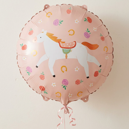 Horse balloon floating with pink curling ribbon against a neutral wall with soft light and shade, close up in square format