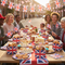 Union Jack party boxes filled with food and treats on a British street party table with bunting