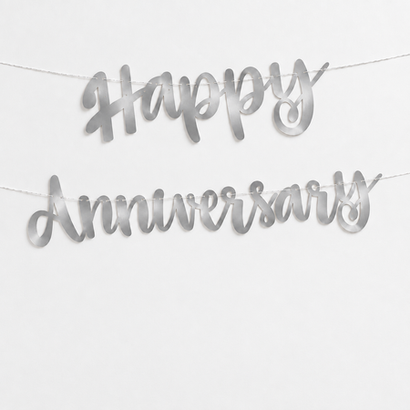 Smooth silver metallic foil-card Happy Anniversary letter banner displayed against a soft white wall