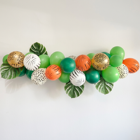 Jungle balloon garland against an off-white wall with soft light and shade, in square format