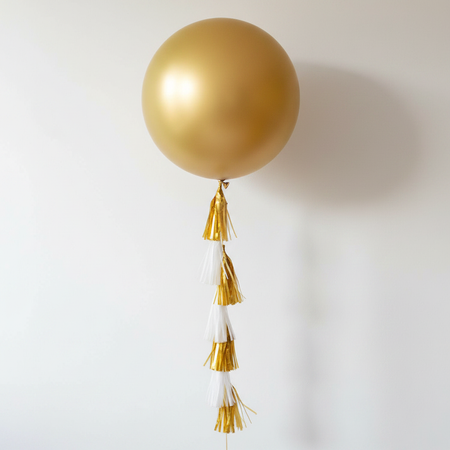 Large Gold Balloon with Tassel Tail on White Wall Background