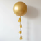 Large Gold Balloon with Tassel Tail on White Wall Background