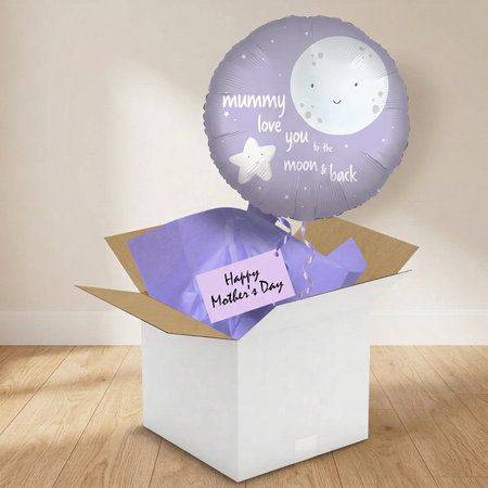 Mummy moon-and-stars balloon and gift box on a wooden floor against a softly lit neutral wall, in square format