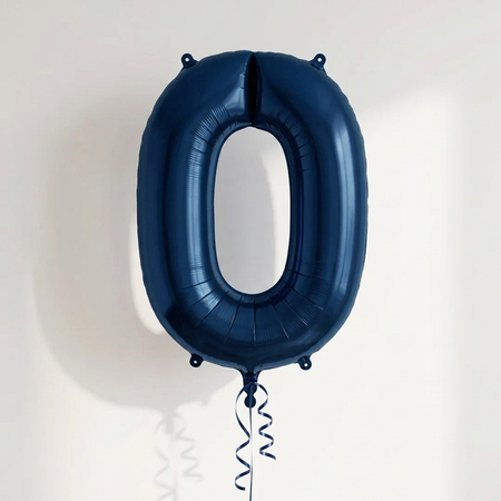 Navy blue number 0 balloon with blue curling ribbon against a softly lit neutral wall