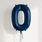 Navy blue number 0 balloon with blue curling ribbon against a softly lit neutral wall