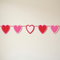 Original five-heart bunting against a cream wall with light and shade, in square format