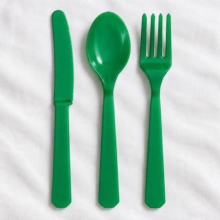 Overhead view of green cutlery on a white tablecloth with soft light and shade, in square format